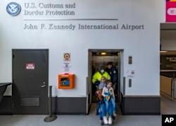 Four-year-old Omar Abu Kuwaik, and his aunt Maha Abu Kuwaik, both from Gaza, are escorted through John F. Kennedy International Airport after departing a flight from Egypt on Wednesday, Jan. 17, 2024, in New York. (AP Photo/Peter K. Afriyie)