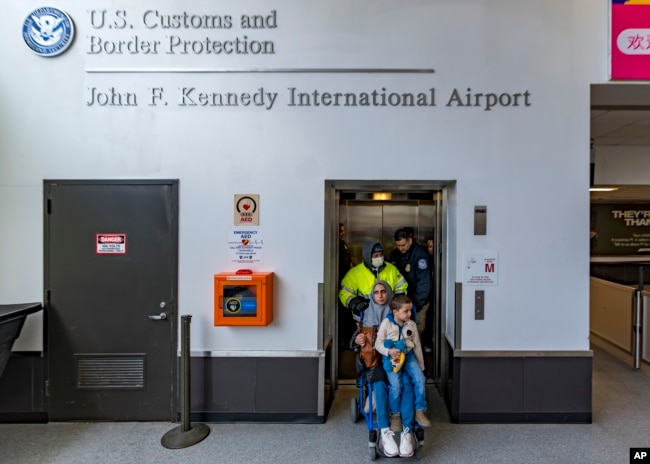 Four-year-old Omar Abu Kuwaik, and his aunt Maha Abu Kuwaik, both from Gaza, are escorted through John F. Kennedy International Airport after departing a flight from Egypt on Wednesday, Jan. 17, 2024, in New York. (AP Photo/Peter K. Afriyie)