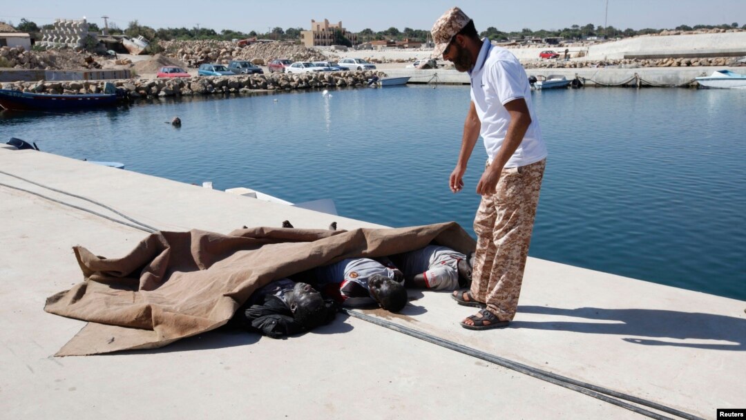 A man inspects the bodies of three African migrants that were recovered by the Libyan coastguard after their boat sunk off the coastal town of Garaboly, east of Tripoli, Sept. 15, 2014.