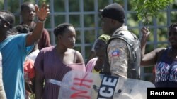 A resident stares at a Haitian National Police officer during a protest outside of Monte Cristo Hotel, designated as a coronavirus quarantine facility, in Port-au-Prince, Haiti March 12, 2020. Haiti has yet to confirm any cases of the new virus. 