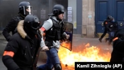 Cảnh sát chống bạo động chạy ngang qua những thùng rác bị phóng hỏa bởi những người biểu tình áo gi-lê vàng ở Paris, Pháp, ngày 9 tháng 2, 2019.