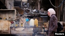 Seorang perempuan berjalan melewati penjual BBM di Ein Terma, distrik Ghouta timur, Suriah, 26 Februari 2019. (Foto: Reuters)