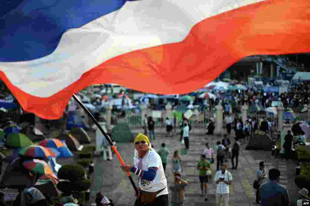 Một người biểu tình chống chính phủ Thái Lan phất cờ ở một địa điểm diễn ra biểu tình tại Tượng đài Chiến thắng ở trung tâm Bangkok. Tòa án đã trao quyền quyết định có nên trì hoãn cuộc bầu cử hay không lại cho chính phủ và ủy ban bầu cử, khiến cho cuộc bỏ phiếu gây tranh cãi đối mặt với tương lai bất định.