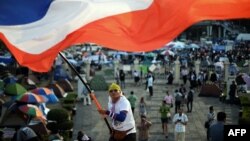 A Thai anti-government protester waves a national flag during ongoing rallies at a protest site at Victory Monument in downtown Bangkok, Jan. 24, 2014. 