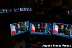 Des images du président français Emmanuel Macron sont vues sur des écrans d'ordinateur alors qu'il prononce son discours télévisé du Nouvel An à la nation depuis l'Elysée, à Paris, le 31 décembre 2021.