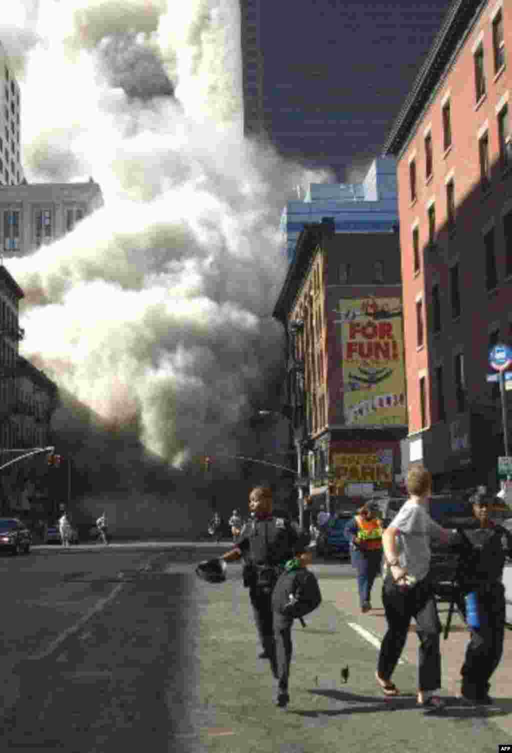 Police officers and civilians run away from New York's World Trade Center after an additional explosion rocked the buildings Tuesday morning, Sept. 11, 2001. In unprecedented show of terrorist horror, the 110-story World Trade Center towers collapsed in a