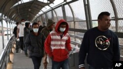 Central American migrants seeking asylum, some wearing protective face masks, return to Mexico via the international bridge at the U.S-Mexico border that joins Ciudad Juarez and El Paso, March 21, 2020.