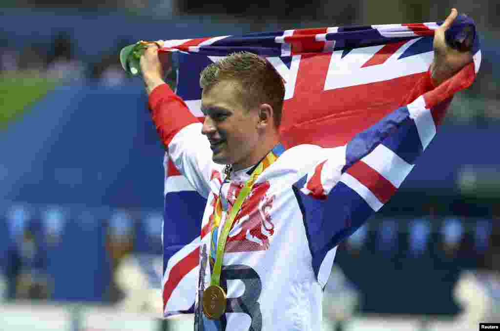 Perenang Inggris Adam Peaty berpose dengan bendera nasional setelah meraih medali emas. (Reuters/Michael Dalder)&nbsp;