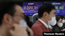 Currency dealers work in front of an electronic board showing the Korea Composite Stock Price Index (KOSPI) at a dealing room of a bank, in Seoul, South Korea, Jan. 6, 2021.