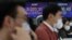 Currency dealers work in front of an electronic board showing the Korea Composite Stock Price Index (KOSPI) at a dealing room of a bank, in Seoul, South Korea, Jan. 6, 2021.