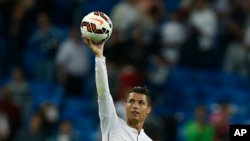 FILE - In this Sept. 23, 2014 file photo Real's Cristiano Ronaldo holds the ball as he celebrates his four goals during a Spanish La Liga soccer match between Real Madrid and Elche at the Santiago Bernabeu stadium in Madrid, Spain. Ronaldo is one of the t