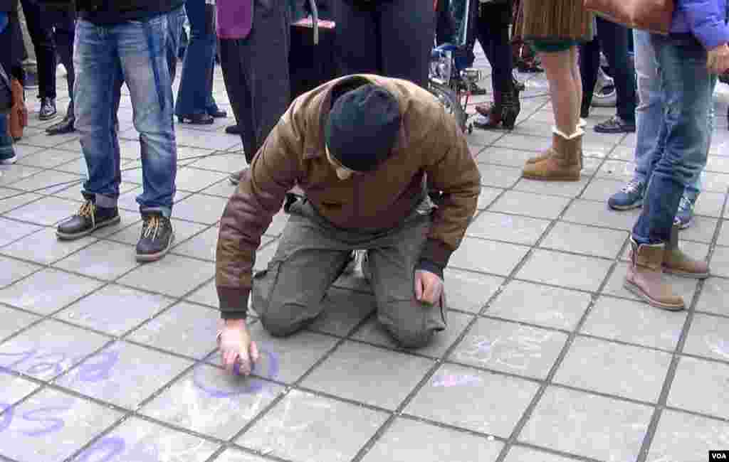 People scrawl messages on the sidewalk at the Place de la Bourse in downtown Brussels in response to the terrorist attacks that left dozens of people dead, March 23, 2016. (L. Bryant/VOA)