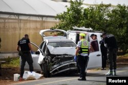 Israeli medics and policemen check a damaged car at the scene of a shooting attack, in the Jordan Valley in the Israeli-occupied West Bank