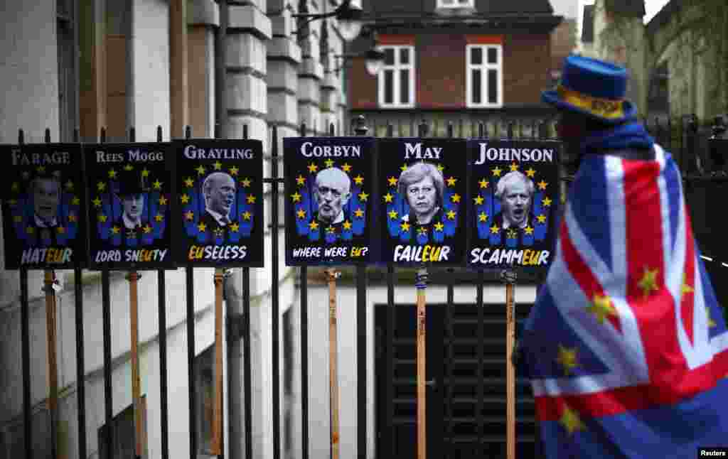 An anti-Brexit demonstrator walks past protest signs in London.