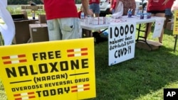 ARCHIVO - Carteles anuncian medicamento contra sobredosis de drogas en un evento de salud en Charleston, Virginia Occidental, el 26 de junio de 2021.