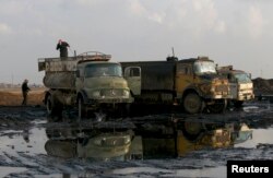 FILE - A man stands on a truck near oil fields in Al-Rmelan, Qamshli province, Syria, Nov. 11, 2013. Syrian regime is said to keep tight monopoly on oil transports, ensuring areas under government control receive adequate supplies.