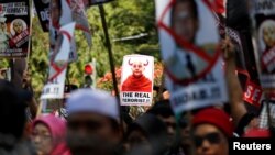 FILE - Protesters carry placards with pictures of Wirathu, a nationalist Buddhist monk known for railing against Muslims on social media and elsewhere, during a protest near the Myanmar embassy against the treatment of the Rohingya Muslim minority, in Jakarta, Indonesia, Sept. 8, 2017. 