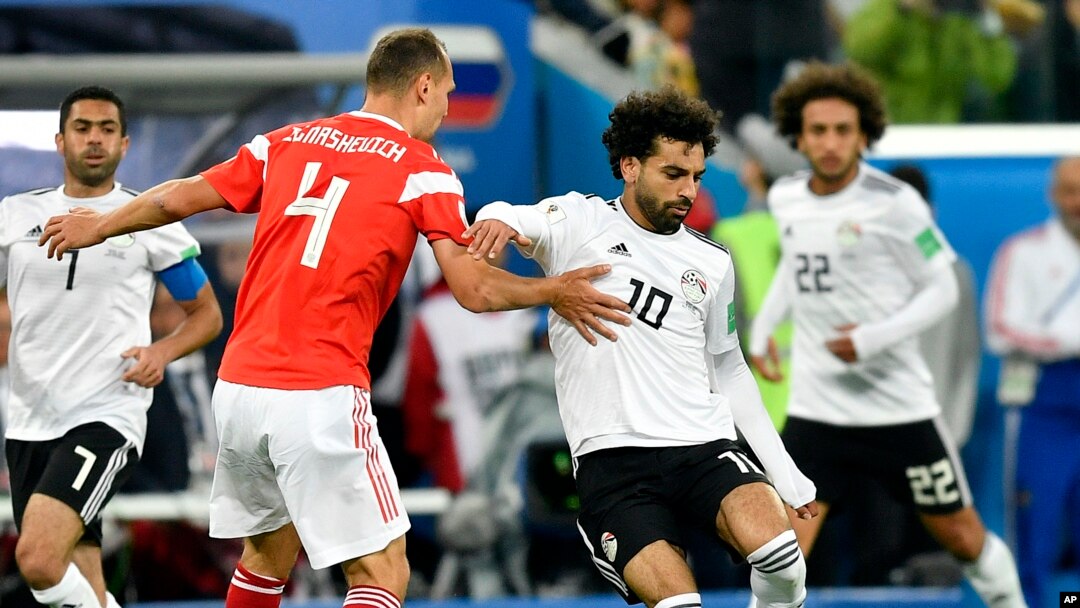 Pesepak bola Rusia, Sergei Ignashevich (kiri), dan Mohamed Salah dari Mesir (kanan) berebut menguasai bola dalam laga penyisihan Grup A antara Rusia dan Mesir di Piala Dunia 2018 di Stadion St. Petersburg, Rusia, 19 Juni 2018.