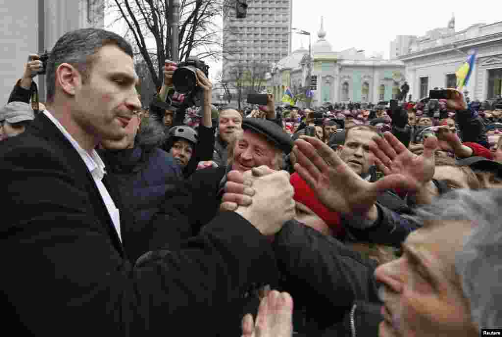 Pemimpin oposisi Ukraina dan kepala partai UDAR, Vitaly Klitschko (kiri), menyapa para demonstran anti-pemerintah di luar gedung parlemen di Kyiv.