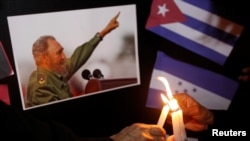 FILE - People place candles beside a picture of Fidel Castro, as part of a tribute, following the announcement of the death of the Cuban revolutionary leader, in Tegucigalpa, Honduras, Nov. 26, 2016.