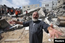 FILE - A Palestinian man reacts as rescue workers search for victims under the rubble of a house, which witnesses said was destroyed in an Israeli airstrike, in Khan Younis in the southern Gaza Strip, July 29, 2014.