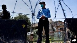 A police officer and paramilitary soldier stand guard at a checkpoint of a restricted area to help to contain the spread of new coronavirus, in Islamabad, Pakistan, June 13, 2020. 