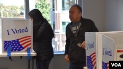 Boris Obed Ávila, [derecha] vota junto a su hija Stephanie Ávila en un centro de votación de Arlington, Virginia, el viernes 25 de octubre de 2024, luego de que ella se registrara para votar por primera vez.