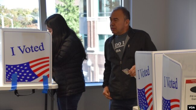 Boris Obed Ávila, [derecha] vota junto a su hija Stephanie Ávila en un centro de votación de Arlington, Virginia, el viernes 25 de octubre de 2024, luego de que ella se registrara para votar por primera vez.