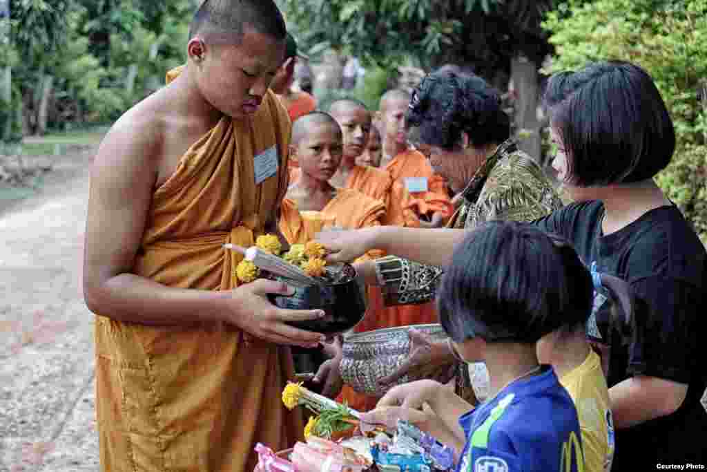 A group of recently ordained novice Buddhist monks walk barefoot on a daily alms round through a rural Thai village for their food. The youngsters have chosen to ordain as monks for the summer holidays. (Photo taken by Matthew Richards in Thailand)