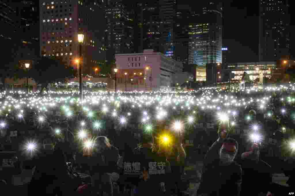Teachers and pro-democracy supporters light their mobile phones as they take part in a rally to support teachers at Edinburgh Place in the Central district of Hong Kong.