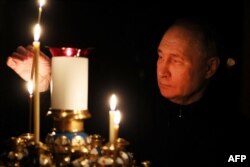 FILE— In this pool photograph from the Russian state agency Sputnik, President Vladimir Putin lights a candle at a church of the Novo-Ogaryovo state residence outside Moscow on March 24, 2024, during a national day of mourning following the attack in the Crocus City Hall.