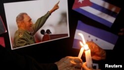 People place candles beside a picture of Fidel Castro, as part of a tribute, following the announcement of the death of the Cuban revolutionary leader, in Tegucigalpa, Honduras, Nov. 26, 2016.