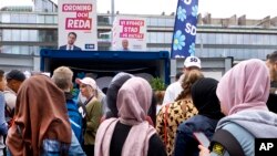 Young women, many wearing headscarves, listen to a party member of the right-wing Sweden Democrats in Stockholm, Sweden, Aug. 31, 2018. 