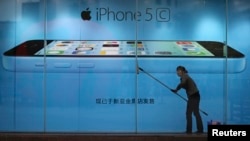 FILE - A worker cleans the windows in front of an iPhone 5C advertisement at an Apple store in Kunming, Yunnan province, China.