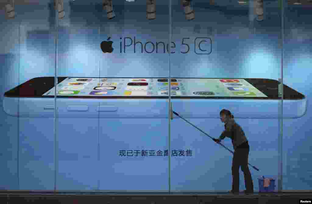 2013年10月27日，在云南省昆明的一家苹果商店的iPhone 5C广告前，一名工人擦玻璃。