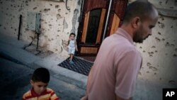 FILE - A Libyan family stands next to their house within Area 2 in Sirte , Libya, July 16, 2012. Sirte, the hometown of the country's late dictator Moammar Gadhafi and the last regime stronghold to fall during the revolution.