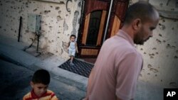 Un père et ses enfants à l’extérieur de leur maison dans la zone 2 à Syrte, en Libye, le 16 juillet 2012.