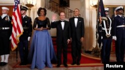 El presidente francés, Francois Hollande, saluda en la Casa Blanca, donde le fue ofrecido un banquete de Estado. Le acompañan la primera dama Michelle Obama y el presidente Barack Obama.