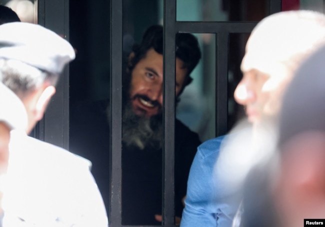 Seorang pria yang menurut sumber keamanan membawa bersenjata dan menyandera sambil menuntut pengembalian deposito banknya, terlihat dari balik pintu Bank Federal Lebanon di Hamra, Lebanon, 11 Agustus 2022. (REUTERS/Mohamed Azakir)