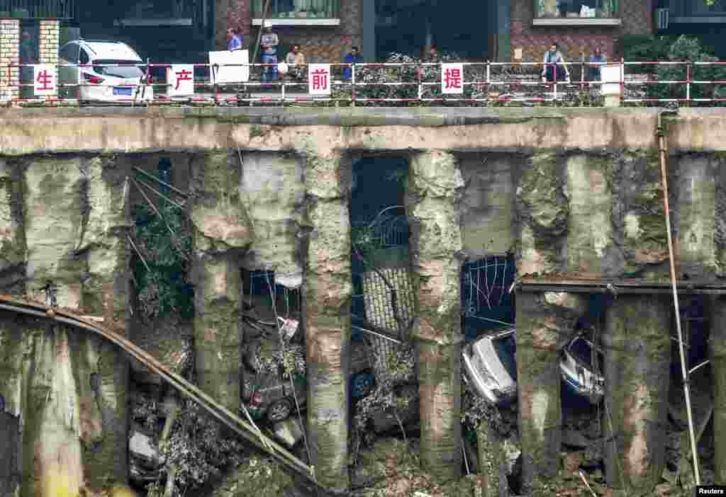 Cars are seen in a sunken open-air parking lot after heavy rainfall hit Chengdu, Sichuan province, China. Four cars fell into the pit and one was left stuck on the edge of a railing as the ground sunk, according to local media.