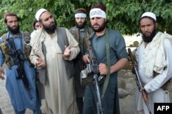 FILE - Afghan Taliban militants stand with residents as they took to the street to celebrate a cease-fire on the outskirts of Jalalabad on June 16,2018.