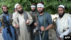FILE - Afghan Taliban militants stand with residents as they took to the street to celebrate a cease fire on the outskirts of Jalalabad on June 16,2018.