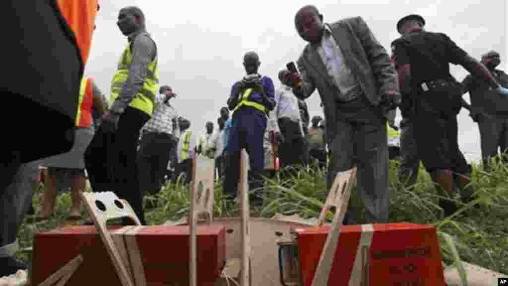 People take photographs of flight data recorders recovered from the wreckage of a passenger jet which crashed soon after take off from Lagos airport.