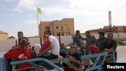 People ride on the back of a truck at the border town of Tal Abyad, Syria, Oct. 14, 2019. 