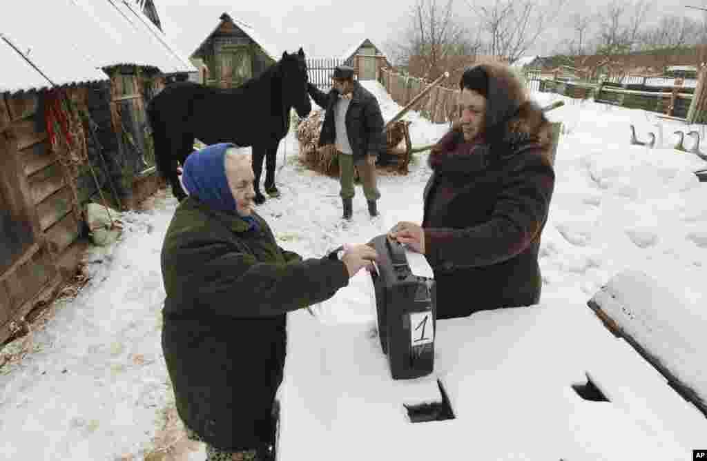 A woman casts her ballot in a mobile ballot box outside her house in the village of Oktyabrskoye, about 440 km (273 miles) from Moscow, March 4, 2012. (Reuters)