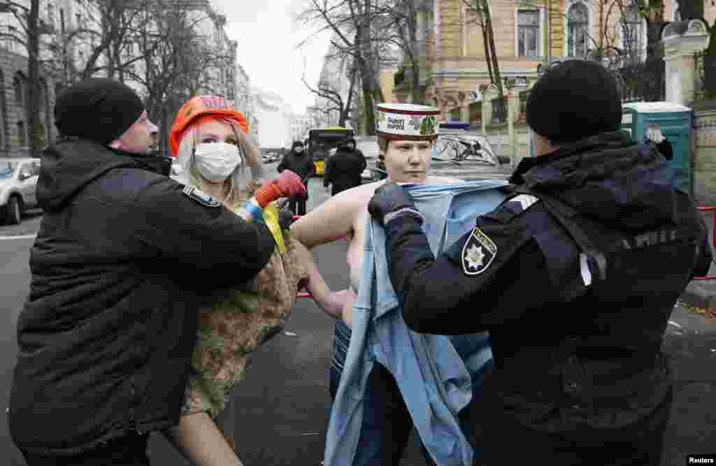 우크라이나 키예프의 대통령실 부속 행정건물 주변에서&nbsp;여성인권단체 &#39;페멘&#39; 회원들이 반나체 시위를 벌이다 경찰관들의 저지를 당하고 있다.