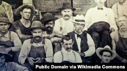 Foto histórica de Jack Daniel (con sombrero blanco) sentado junto a George Green, el hijo de Nathan "Nehest" Green.