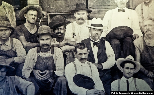 Historic photo of Jack Daniel (in white hat) seated next to George Green, the son of Nathan