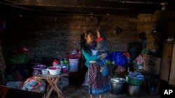 Alba Organiz holds her son Rudy Anibal while preparing food for guests who have come to pay their respects to the family of Santa Perez, in Comitancillo, Guatemala, Jan. 27, 2021. 