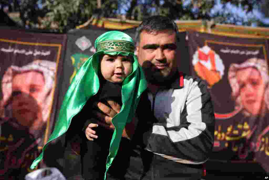 A Shiite Muslim man holds up his baby with Arabic dress, in a street during a procession to mark Ashoura in Kabul, Afghanistan.